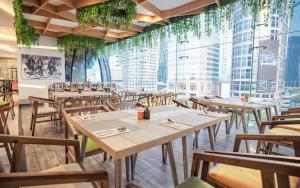 a restaurant with tables and chairs and tall windows at HARRIS Suites fx Sudirman in Jakarta