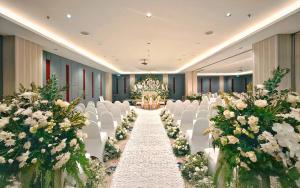a banquet hall with white chairs and a aisle with flowers at HARRIS Suites fx Sudirman in Jakarta +70 photos