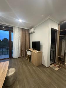 a living room with a television and a desk with a chair at Luso in Batumi