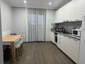 a kitchen with white cabinets and a table and a dining room at Luso in Batumi