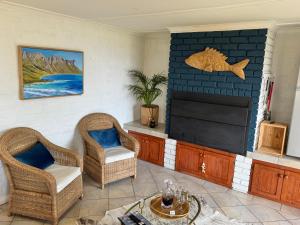 a living room with two chairs and a television at Pebbles & Shells in Kleinmond