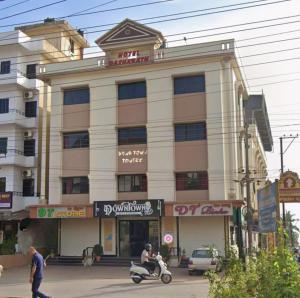 a man riding a scooter in front of a building at Manipal Downtown in Manipal