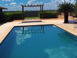 a large blue swimming pool with a wooden deck at Recanto Barretos in Barretos