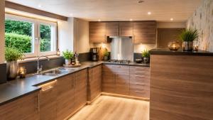 a kitchen with wooden cabinets and a sink at Maison Samree met Indoor Wellness in La-Roche-en-Ardenne