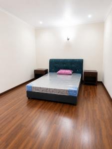 a bed in a room with a wooden floor at Anjung Seri Residence in Masai