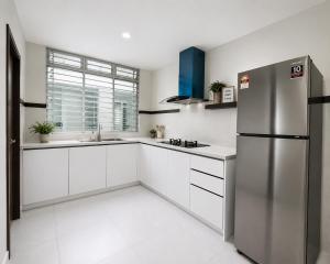 a kitchen with white cabinets and a stainless steel refrigerator at Anjung Seri Residence in Masai