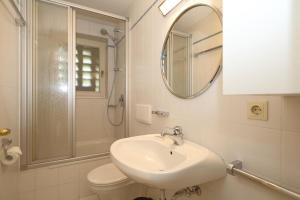 a white bathroom with a sink and a shower at Appartement-Morgenroth in Munkmarsch +25 photos