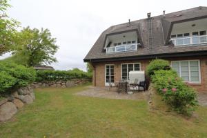 a brick house with a patio and a yard at Appartement-Morgenroth in Munkmarsch