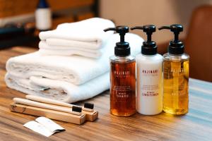 three bottles of essential oils and towels on a table at Osaka Petite Tanuki Inn Neyagawa in Neyagawa