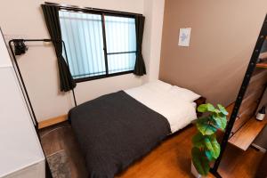 a small bedroom with a bed and a window at Osaka Petite Tanuki Inn Neyagawa in Neyagawa
