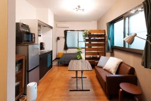 a living room with a couch and a table at Osaka Petite Tanuki Inn Neyagawa in Neyagawa