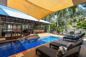 an outdoor swimming pool with chairs and a large umbrella at The Courthouse Bed & Breakfast in Broome