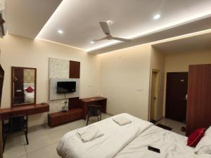 a bedroom with a bed and a desk and a television at Sree Durga Hotel Ramsons International in Mysore +4 photos