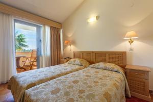 a hotel room with two beds and a balcony at Apartments Bellevue Plava Laguna in Poreč