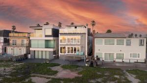 a large house with a sunset in the background at Beachfront Condo on A LowKey Beach in Sunset Beach