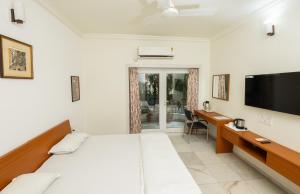 a bedroom with a bed and a desk and a tv at Ishan Apartments 3BHK in Vadodara