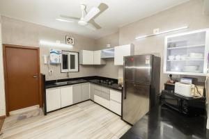 a kitchen with white cabinets and a stainless steel refrigerator at Ishan Apartments 3BHK in Vadodara