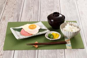 a plate with an egg and a bowl of rice and chopsticks at HOTEL Le Grand in Matsuzaka