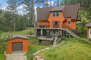 a large orange house with a deck and a yard at Stones Throw in Hill City