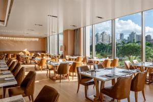 a restaurant with tables and chairs and large windows at Kempinski Hotel Xiamen in Xiamen