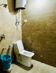 a bathroom with a toilet and a blue bucket at Mata Guest House in Katra