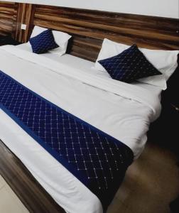 a bed with blue and white sheets and pillows at Mata Guest House in Katra