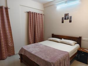 a bedroom with a bed and a window with curtains at Harichandhanam stay in Guruvāyūr