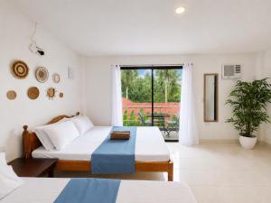 a white room with two beds and a window at Yayay Siargao - Generator & Starlink in General Luna