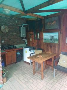 a kitchen with a wooden table in a room at Whispering Gardens in Stilbaai