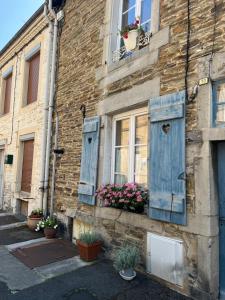 an old building with blue shutters and flowers on it at Gîte Pierre et Meuse in Fumay