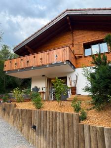 a wooden house with a fence in front of it at Chalet du Lac in Charmey
