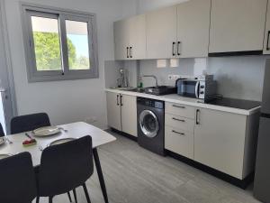a kitchen with a washing machine and a table at Chryso Apts Protaras in Protaras