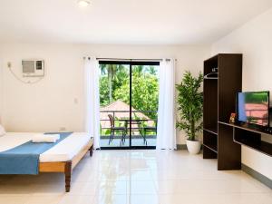 a bedroom with a bed and a tv and a balcony at Yayay Siargao - Generator & Starlink in General Luna