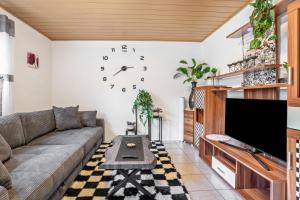 a living room with a couch and a clock on the wall at Kastanie in Selb