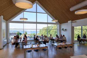 a group of people sitting at tables in a room with large windows at Severin Kursuscenter og Konferencehotel in Middelfart