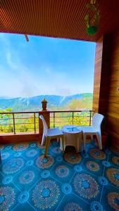 a balcony with a table and two chairs and a view at The Mountain Vault in Barog