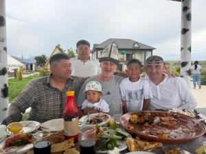 a group of people sitting at a table with food at Guest House Archa in Tong