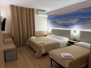 ein Hotelzimmer mit zwei Betten und einem Gemälde an der Wand in der Unterkunft New Alexander Hotel in Genua