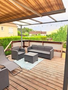 a patio with a couch and chairs on a wooden deck at Le Clos Tranquille in Saint-Privé