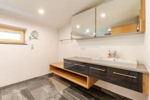 a bathroom with a sink and a mirror at Ferienwohnung La-Wurm mit privatem Whirlpool in Hart im Zillertal +16 photos