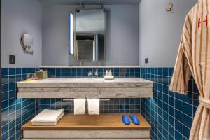 a blue tiled bathroom with a sink and a mirror at Hannah St Hotel Melbourne in Melbourne