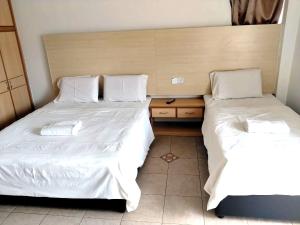 two beds in a room with white sheets at Hotel O Hilltowne in Kampong Kawak