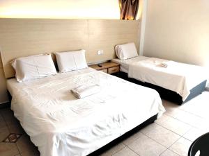 two beds with white sheets in a room at Hotel O Hilltowne in Kampong Kawak