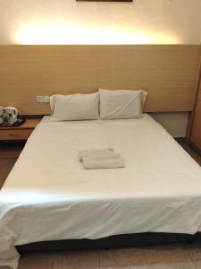 a large white bed with two white towels on it at Hotel O Hilltowne in Kampong Kawak