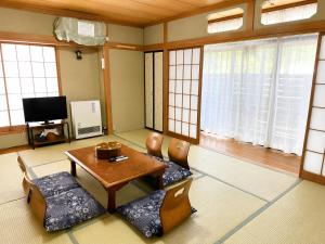 a living room with a table and chairs and windows at Yamanaka Lake Ryozan in Yamanakako