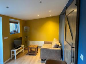a living room with a couch and a television at B&B Historia in Melderslo