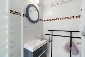 a white bathroom with a sink and a mirror at Le Bois Du Mas in Saint-Aulaye