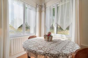 a dining room table with a bird in a basket on a table with windows at Le Bois Du Mas in Saint-Aulaye