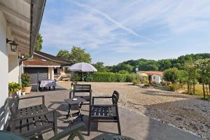 a patio with chairs and tables and an umbrella at Le Bois Du Mas in Saint-Aulaye