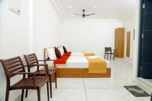 a bedroom with a bed and chairs in a room at RKM Pearl in Cochin